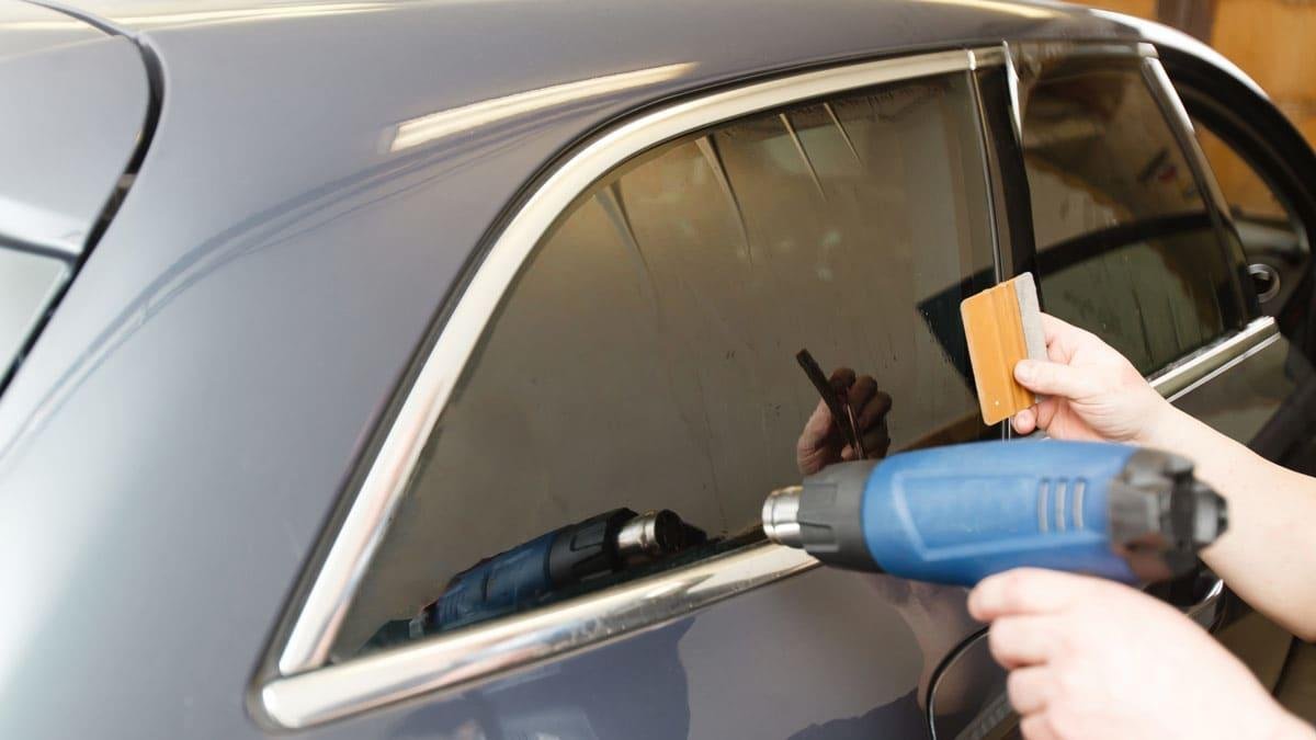 Automotive window tint film being installed on vehicle glass